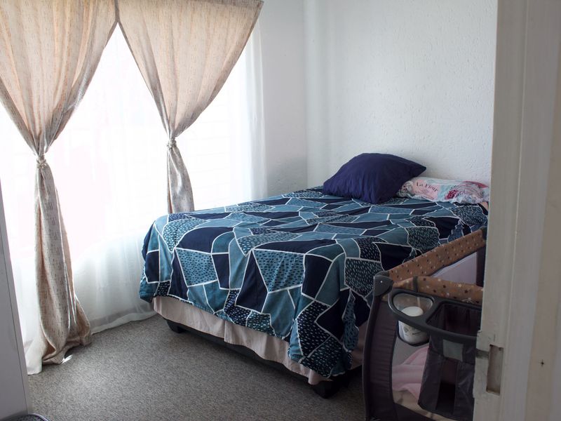 A standard bedroom featuring carpeted flooring and textured walls, providing a functional space with natural light from the window.