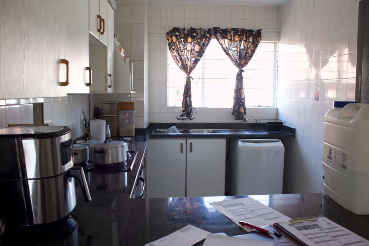 A functional kitchen featuring granite countertops, built-in cabinetry, and a double basin sink with tiled wall finishes.