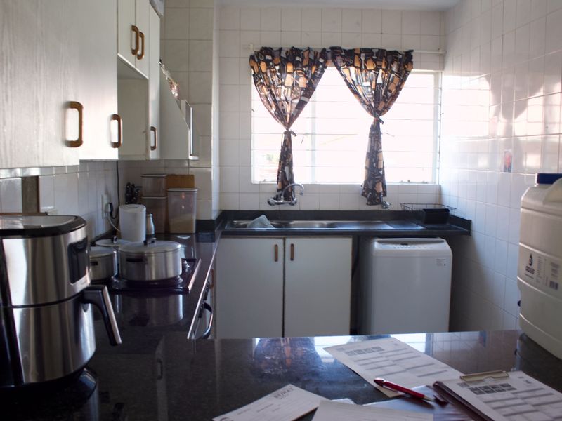 A functional kitchen featuring granite countertops, built-in cabinetry, and a double basin sink with tiled wall finishes.