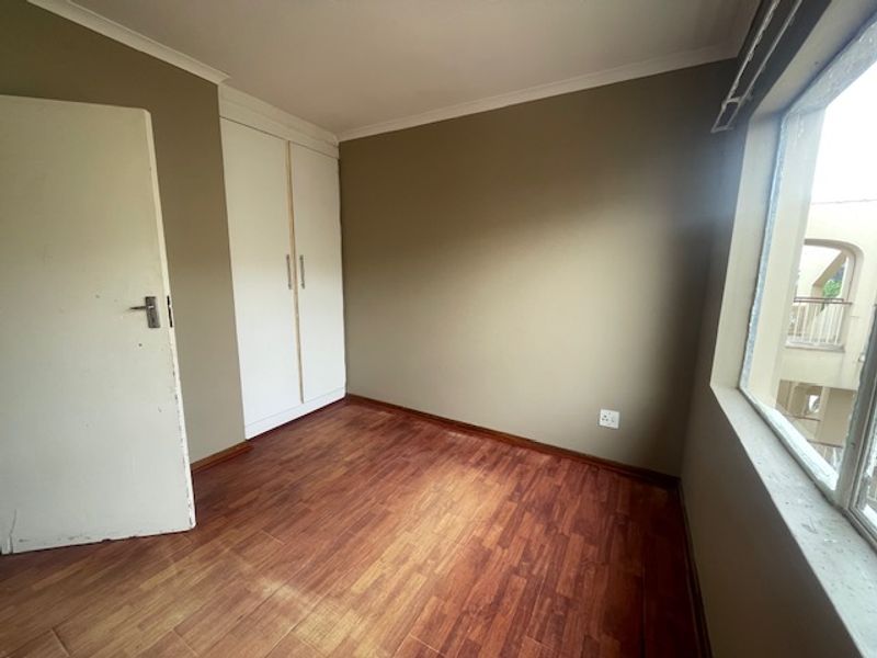 A vacant bedroom featuring laminate flooring and built-in cupboards, offering a neutral canvas ready for personalization.