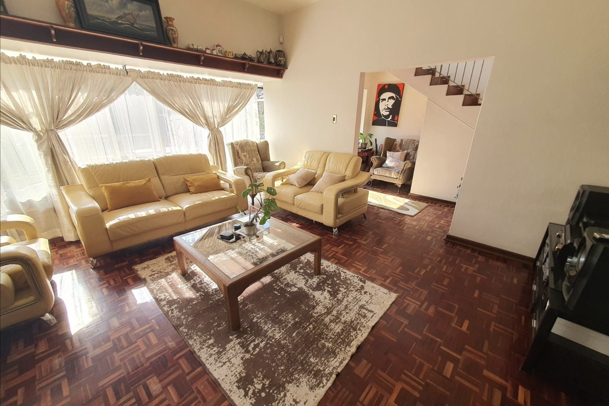 Spacious living room featuring classic parquet flooring, a built-in display shelf, and an open transition to the staircase area.