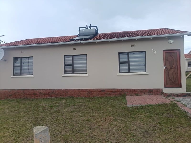 Front elevation of a single-story house featuring a tiled roof, solar water heating system, brick base, and aluminium window frames.