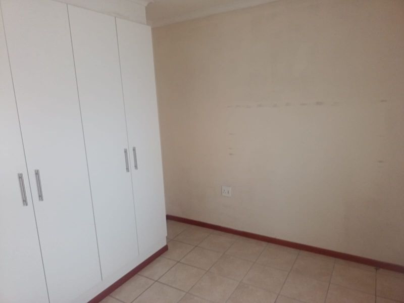 A vacant bedroom featuring built-in cupboards, tiled flooring, and neutral wall finishes, providing a blank canvas for personalization.