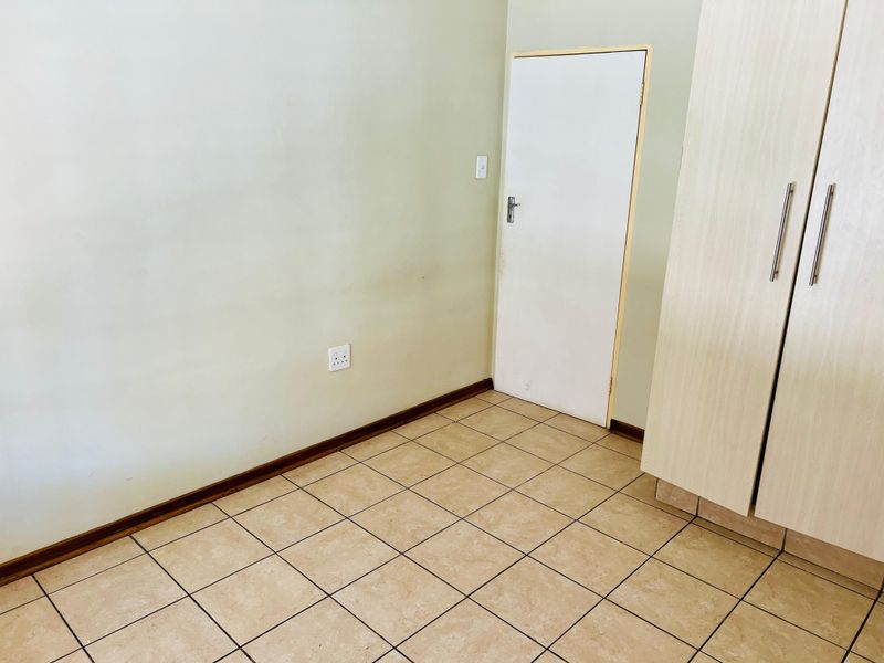 A vacant bedroom featuring tiled flooring and a built-in wardrobe, offering a clean, neutral space ready for personalization.