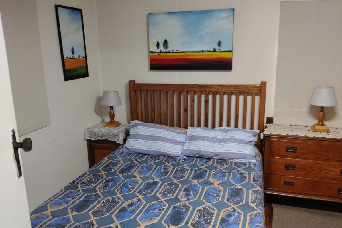 A compact bedroom featuring neutral panelled walls, providing a functional and simple sleeping space.