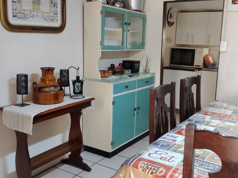 Open plan dining area featuring tiled flooring and a vintage-style built-in cabinet, with an adjacent scullery area visible in the background.