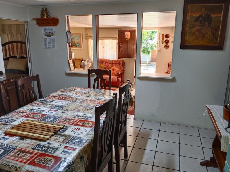 A dining area featuring tiled flooring and a serving hatch that connects to the adjacent living space, providing an open-plan feel.