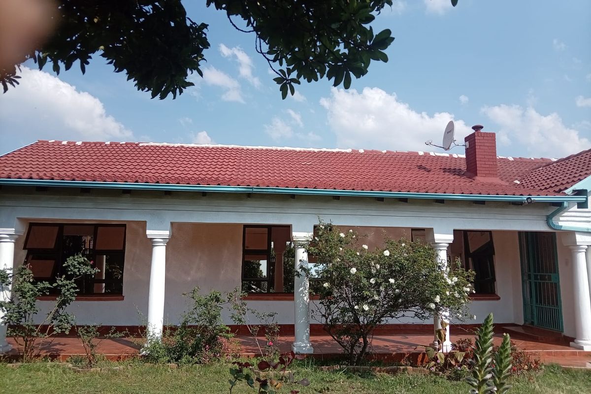 Rear elevation of the house featuring a covered patio with concrete columns, tiled roof, and aluminium window frames overlooking the garden.