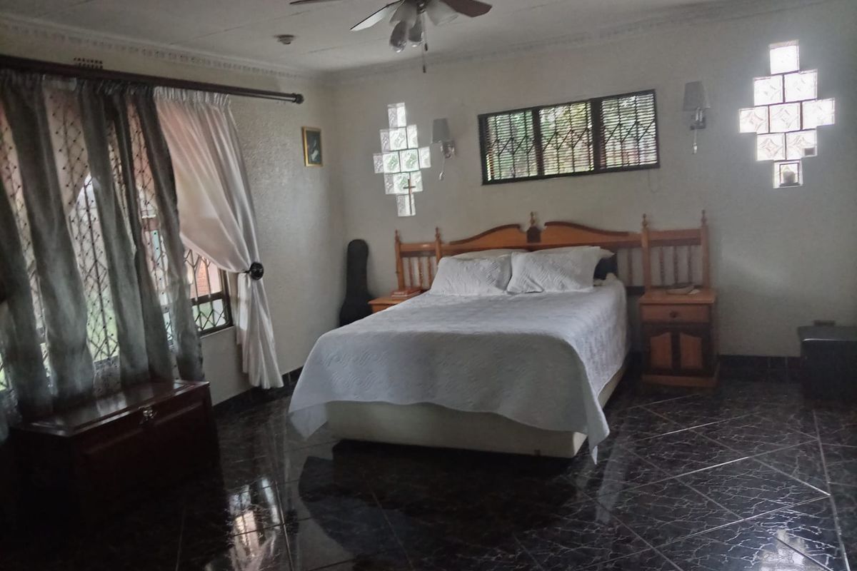 Spacious bedroom featuring dark tiled flooring, decorative ceiling fan, and unique glass block window accents.