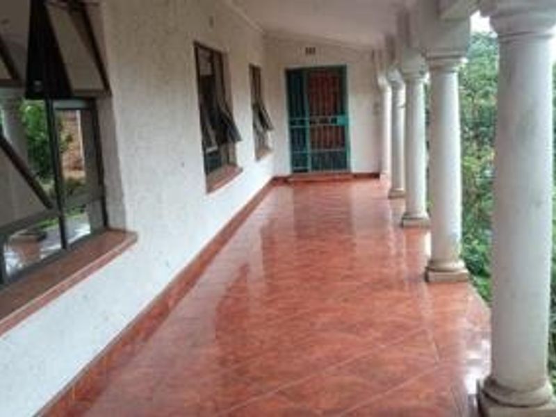 A covered patio featuring tiled flooring, structural columns, and access to the home via a security gate.