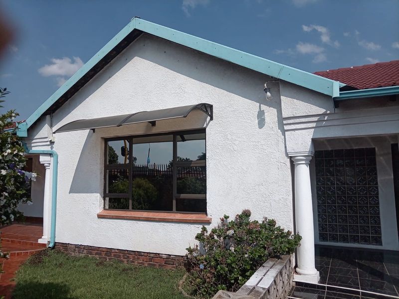 Front facade of a house featuring textured plaster walls, a tiled roof, decorative columns, and a unique glass block entrance feature.