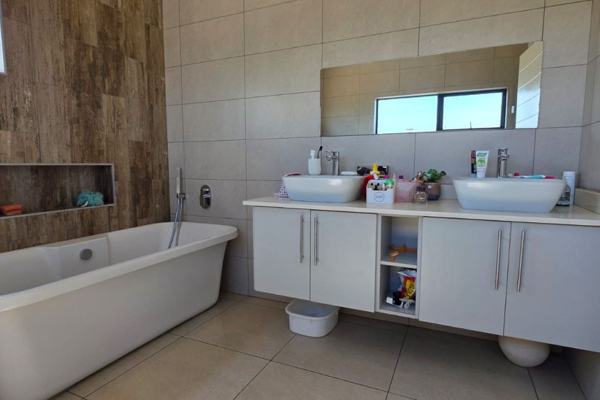 Modern bathroom featuring a freestanding bathtub, a double vanity with integrated sinks, and stylish wood-look and neutral ceramic wall tiling.