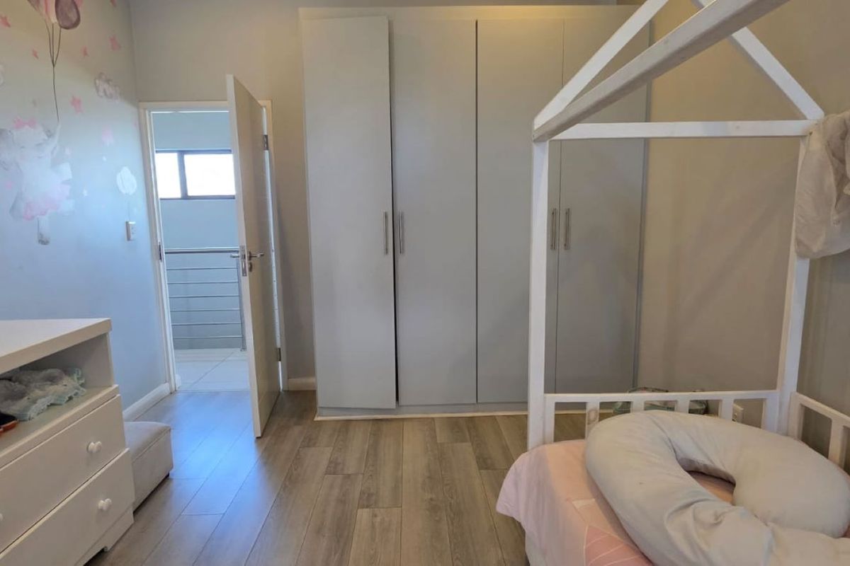 A well-maintained bedroom featuring light-toned laminate flooring and modern built-in cupboards, offering a clean and functional living space.