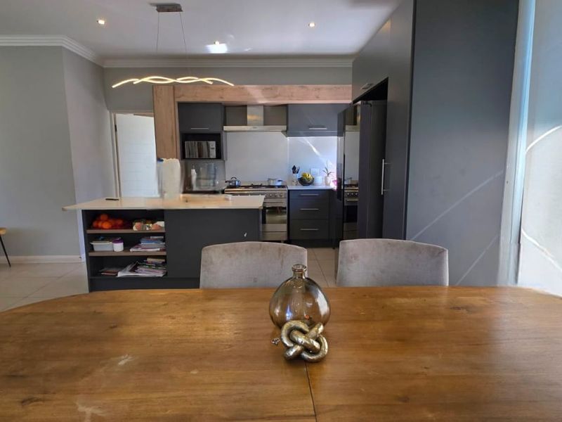 Modern open-plan living and kitchen area featuring a central island, sleek dark cabinetry, and contemporary lighting, creating a functional and cohesive living space.