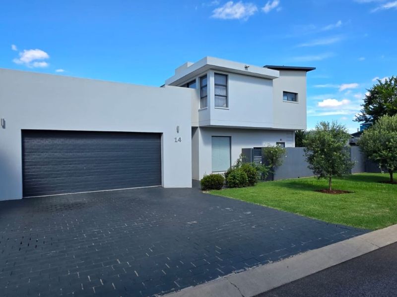 Modern double-story residential home featuring a paved driveway, automated garage, and well-maintained front garden.