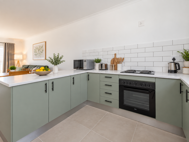 Modern kitchen featuring sage green cabinetry, white quartz countertops, subway tile backsplash, and integrated oven with electric hob.