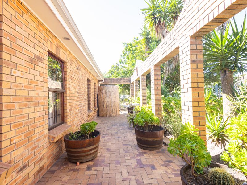 A covered outdoor patio area featuring brick paving and a structural brick pergola, providing a pleasant transition space between the home and garden.