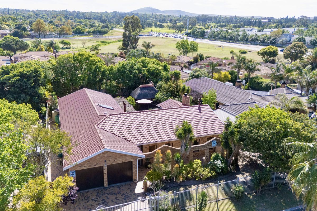 Aerial view of a residential property featuring a tiled roof, double garage, and paved driveway, set within a well-established suburban neighborhood.
