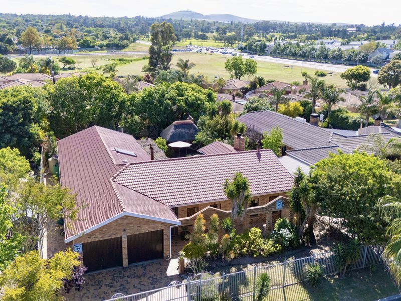 Aerial view of a residential property featuring a tiled roof, double garage, and paved driveway, set within a well-established suburban neighborhood.