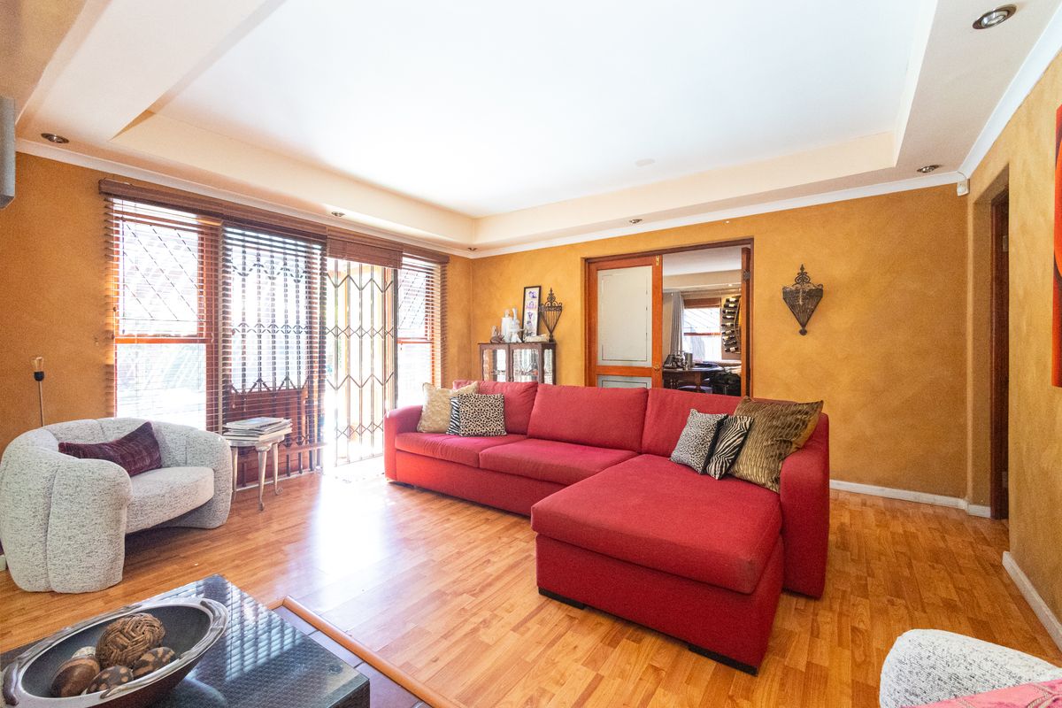 Spacious living room featuring warm-toned textured walls, timber flooring, recessed ceiling lighting, and large sliding doors providing access to the exterior.