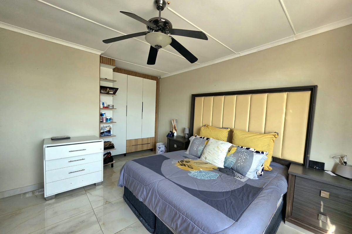 A well-maintained bedroom featuring tiled flooring, a ceiling fan, and a built-in wardrobe with integrated shelving.