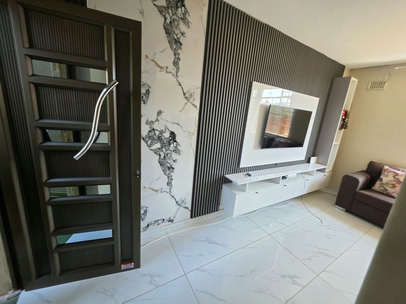 Modern living room featuring a stylish feature wall with marble-look accents, slatted timber paneling, and a sleek built-in media console with tiled flooring.