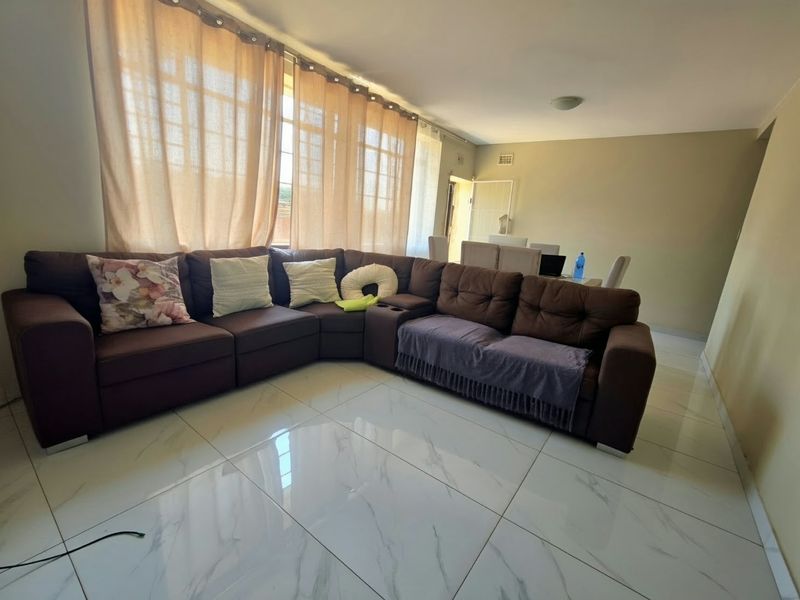 Spacious open-plan living and dining area featuring modern large-format marble-look porcelain floor tiles and ample natural light.