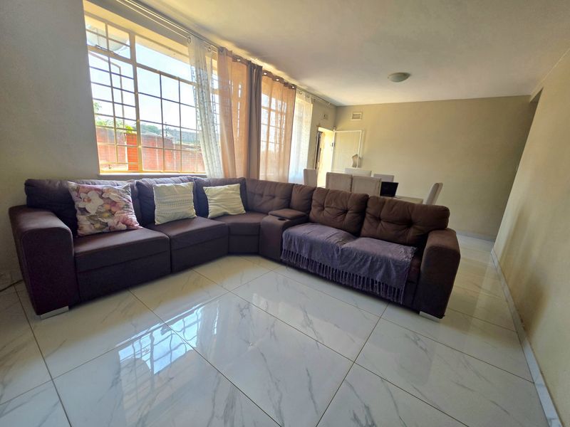 Spacious open-plan living and dining area featuring large-format marble-look floor tiles and expansive steel-framed windows that provide ample natural light.