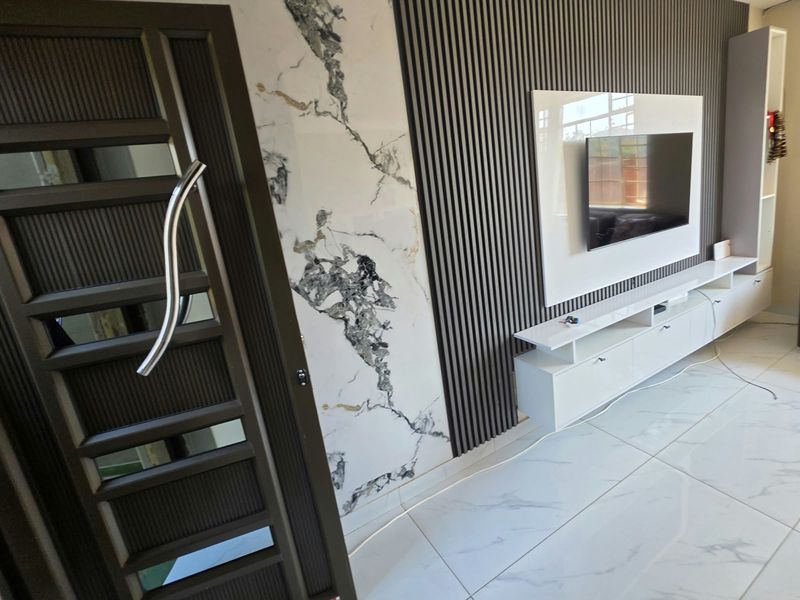 Modern living room featuring a striking marble-look accent wall, slatted timber paneling, built-in media cabinetry, and polished porcelain floor tiles.