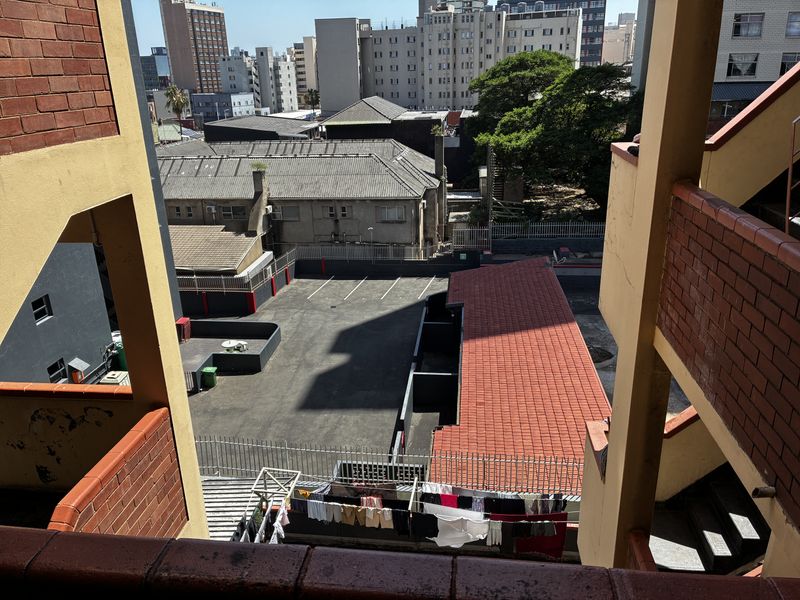 Elevated view overlooking a paved parking area and surrounding urban buildings from an apartment complex balcony.