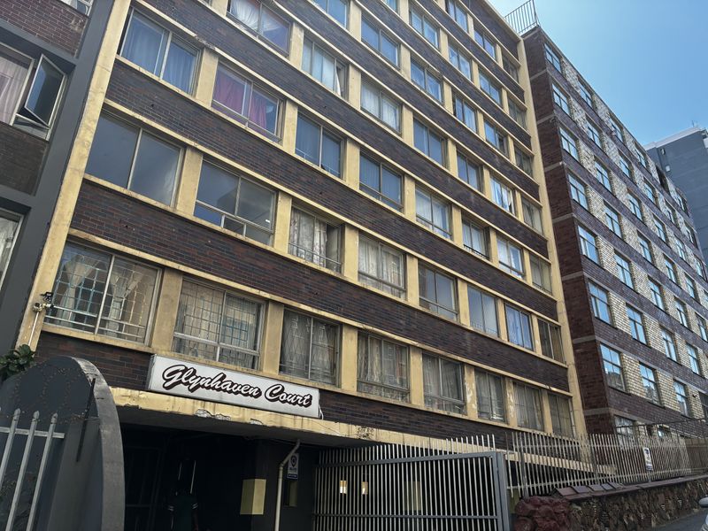 Exterior view of Glynhaven Court apartment building featuring a brick facade, security gate, and multiple window units.
