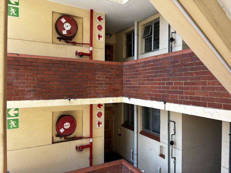 Exterior apartment building hallway featuring brick accents, fire safety equipment, and access to residential units.