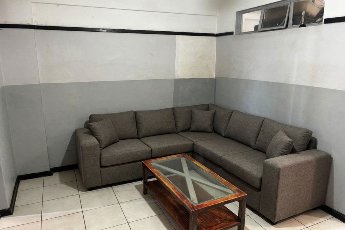 A living room area featuring tiled flooring and a high-level clerestory window, currently requiring cosmetic updates to the wall finishes.