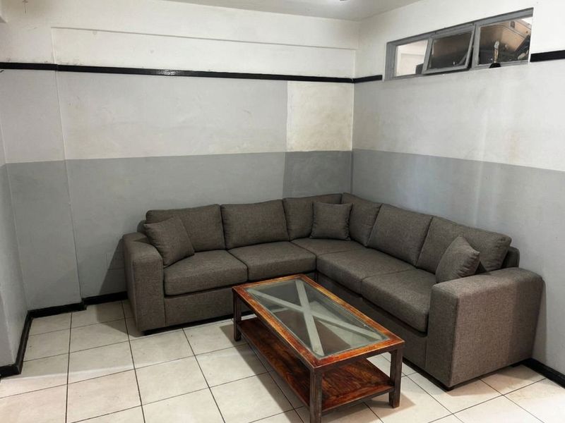 A living room area featuring tiled flooring and a high-level clerestory window, currently requiring cosmetic updates to the wall finishes.