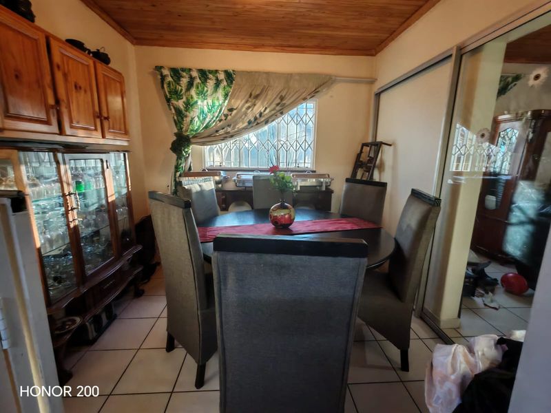 Dining room featuring tiled flooring, timber ceiling, and built-in cabinetry, with natural light provided by a window with security bars.