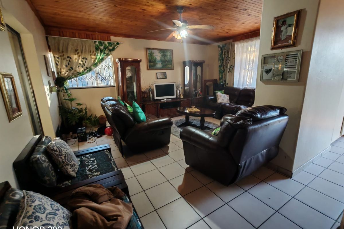 A living room featuring a timber tongue and groove ceiling, ceiling fan, and ceramic floor tiles, providing a traditional and functional living space.