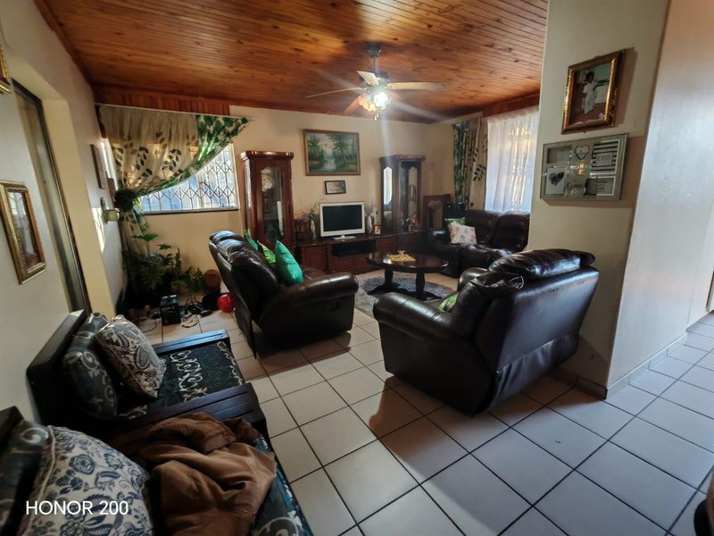 A living room featuring a timber tongue and groove ceiling, ceiling fan, and ceramic floor tiles, providing a traditional and functional living space.
