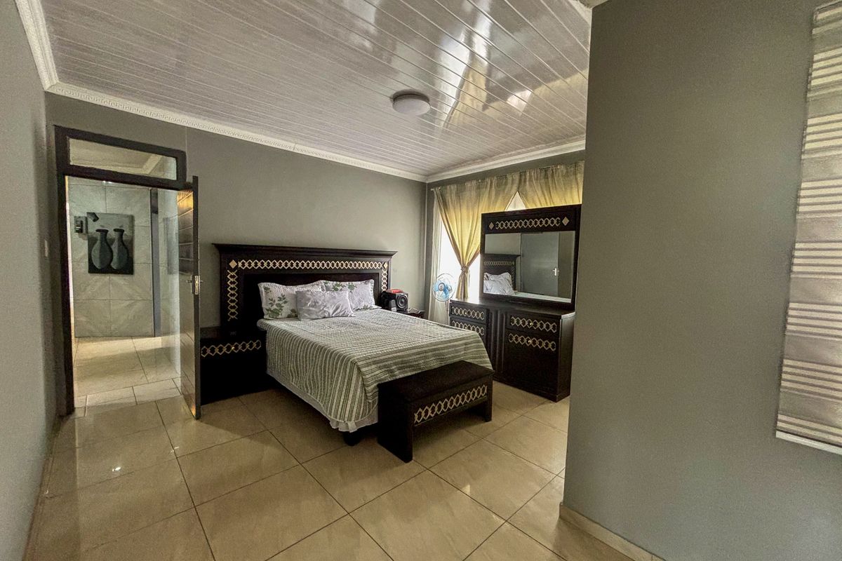 Spacious bedroom featuring large format floor tiles, glossy ceiling panels, and crown molding, providing a neutral foundation for interior design updates.