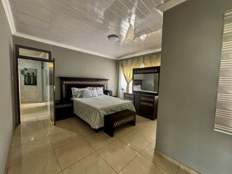 Spacious bedroom featuring large format floor tiles, glossy ceiling panels, and crown molding, providing a neutral foundation for interior design updates.