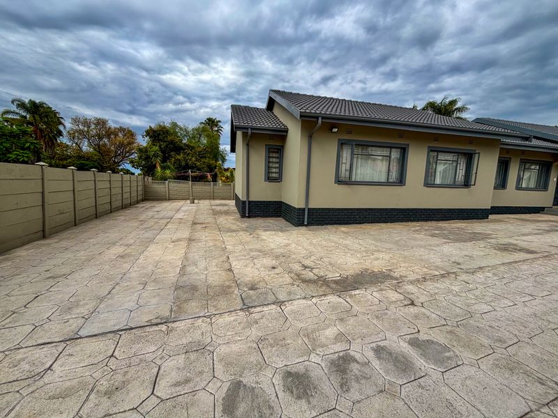 Exterior view of the property featuring a paved driveway, precast concrete boundary wall, and a tiled roof structure.