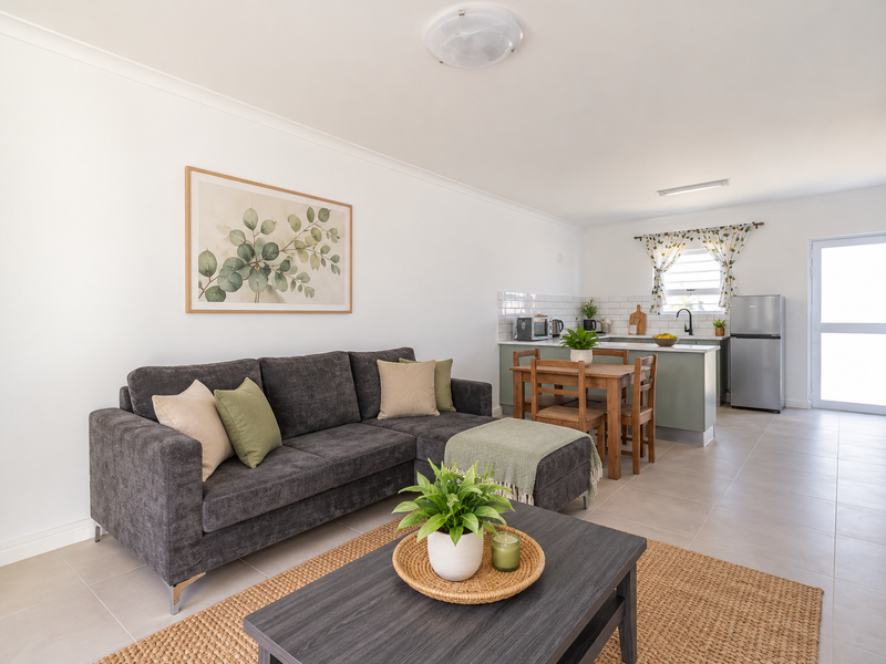 A bright open-plan living and kitchen area featuring neutral tiled flooring, modern cabinetry, and a clean subway tile backsplash.
