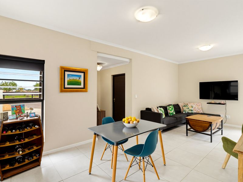 An open-plan living and dining area featuring neutral walls, tiled flooring, and modern flush mount lighting, creating a bright and functional living space.