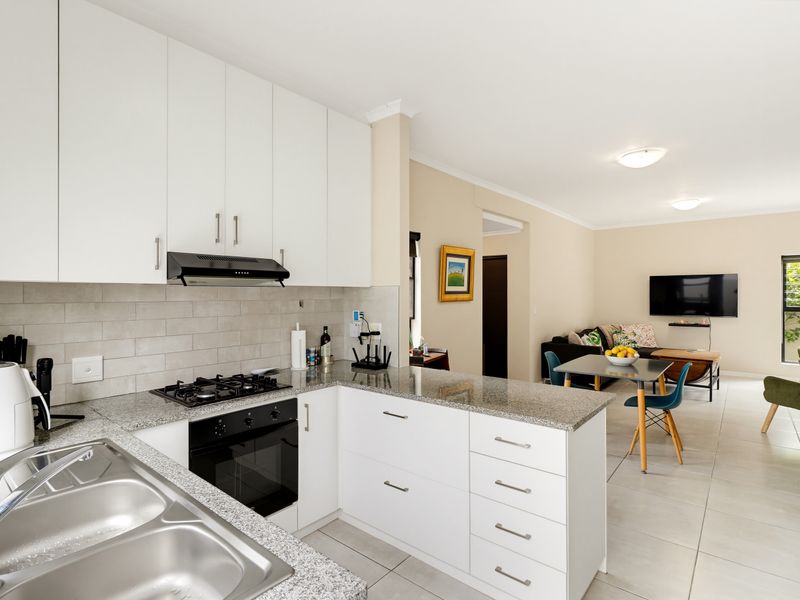 Modern open-plan kitchen featuring granite countertops, gas hob, built-in oven, and ample cabinetry, seamlessly flowing into the adjacent living and dining area.