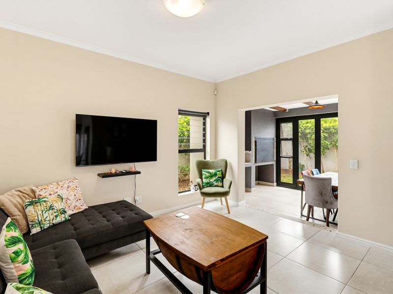 Open plan living area featuring tiled floors and seamless flow to an outdoor patio with a built-in braai.