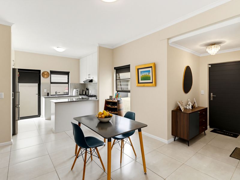 An open-plan living and kitchen area featuring modern cabinetry, granite countertops, and neutral ceramic floor tiles, creating a bright and functional space.
