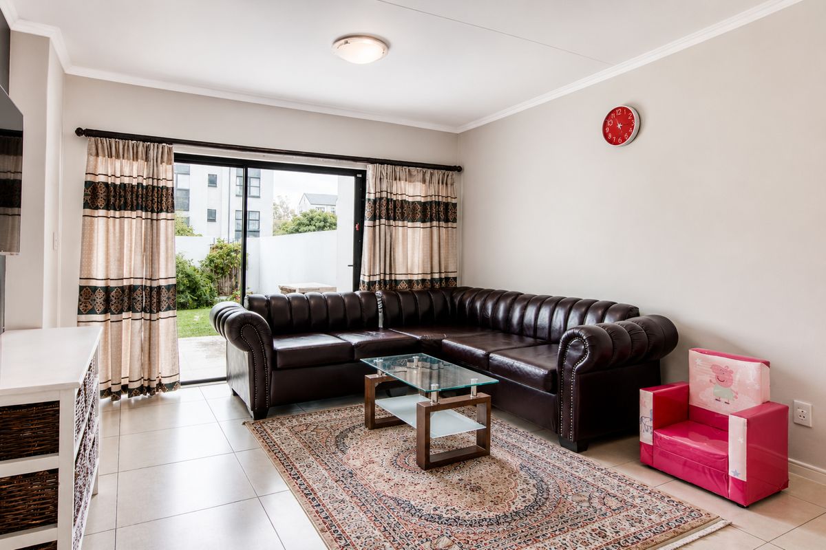 A well-lit living room featuring tiled flooring and a large sliding glass door that provides direct access to the outdoor patio area.