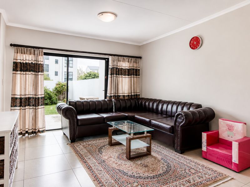 A well-lit living room featuring tiled flooring and a large sliding glass door that provides direct access to the outdoor patio area.