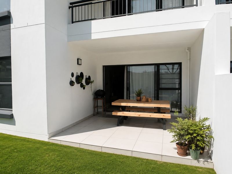A clean, tiled ground-floor patio area featuring a sliding glass door entrance and access to a private garden space.