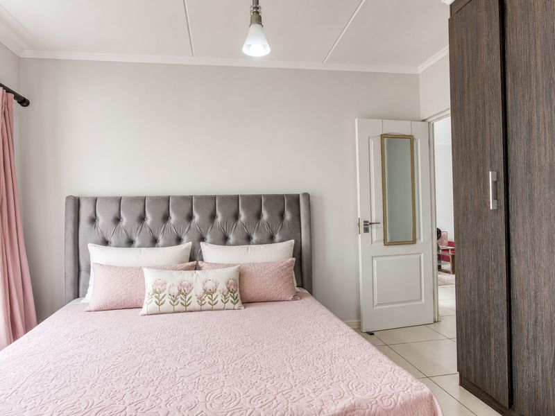 A well-maintained bedroom featuring tiled flooring, a built-in wardrobe, and neutral wall finishes, offering a clean and functional living space.