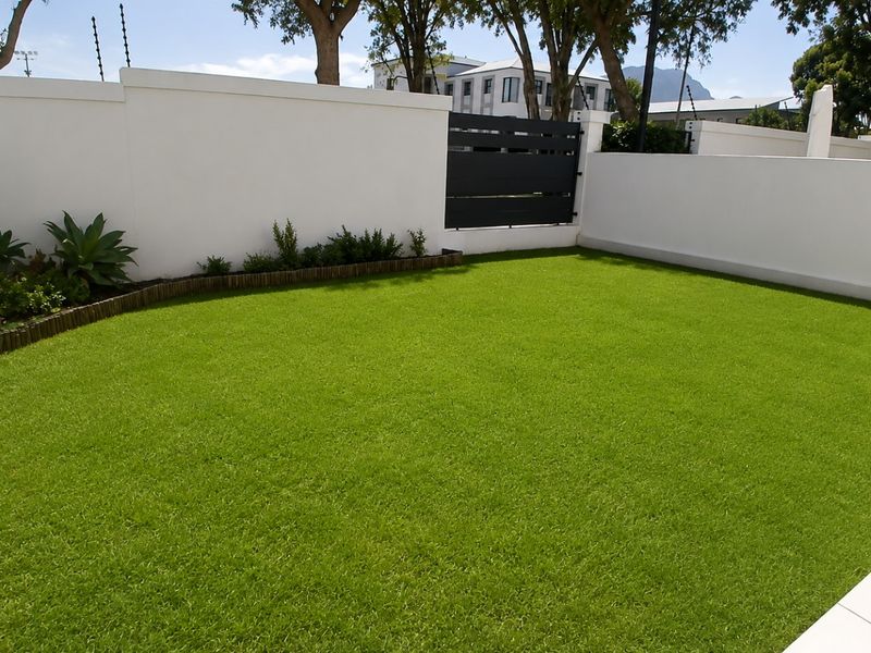A well-maintained private garden featuring artificial turf, clean boundary walls, and secure perimeter fencing.